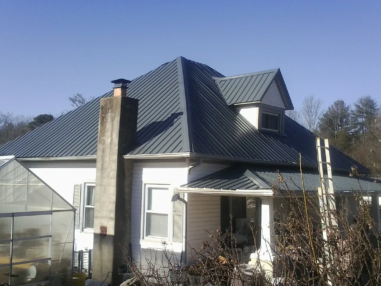 Dark blue standing seam metal roof on a white farmhouse with dormer — Slate & Tile Roof Repair by Roofing Brothers in Le Grand