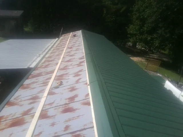 Old rusted panels beside newly installed green metal roofing — Wind Damage Roof Repair by Roofing Brothers in Le Grand