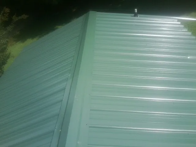 New green metal panels meeting at the ridge of a roof — Flat Roof Repair work by our crew in Le Grand
