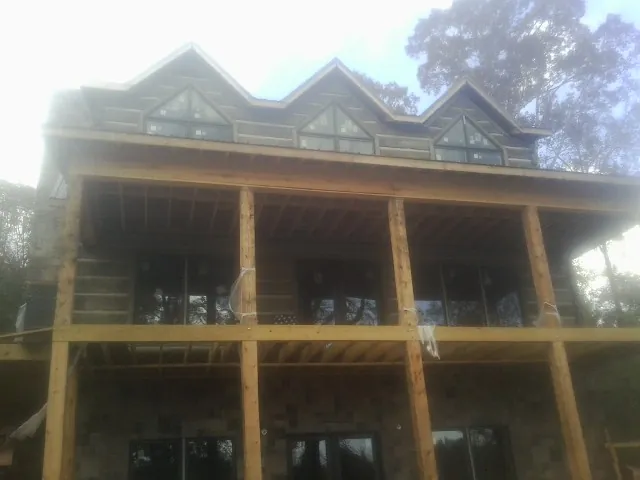 Dormers and porch framing on a large log home under construction — Roof Coating work by our crew in Le Grand