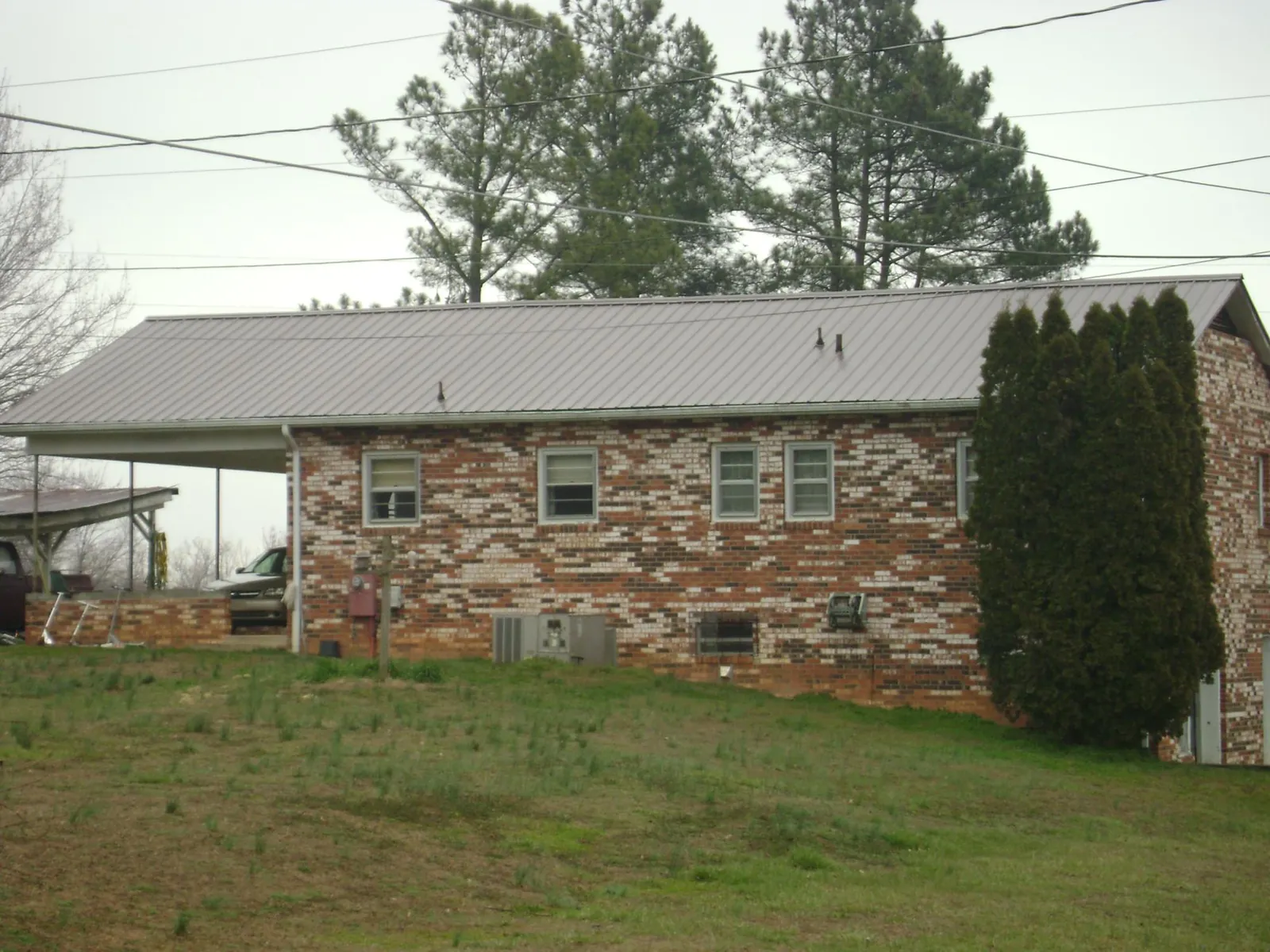 Gray metal roof on a brick split level home with a carport in Le Grand
