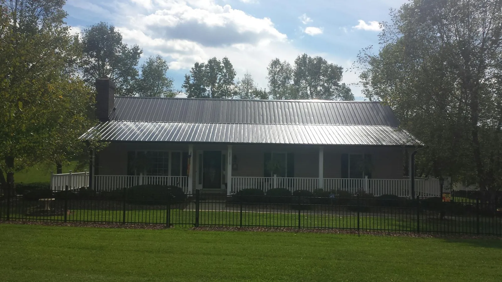 Gray metal roof on a brick ranch with a full width front porch — Gutter Guard Installation work by our crew in Le Grand