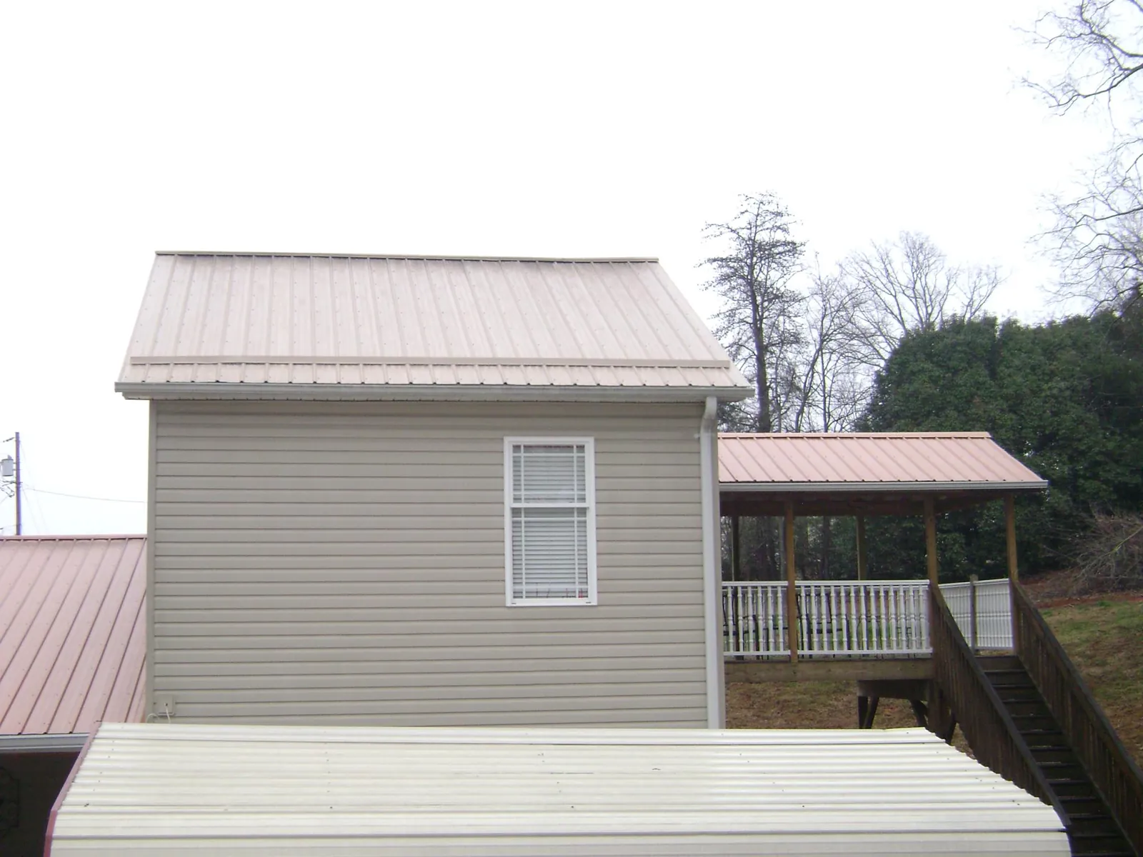 Tan metal roofs on a two story addition and attached porch, from a Roof Replacement job in Le Grand