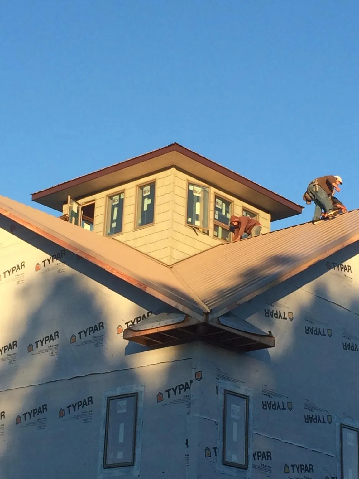 Roofers working around a rooftop cupola on a new metal roof at sunset — Roof Waterproofing in Le Grand by Roofing Brothers